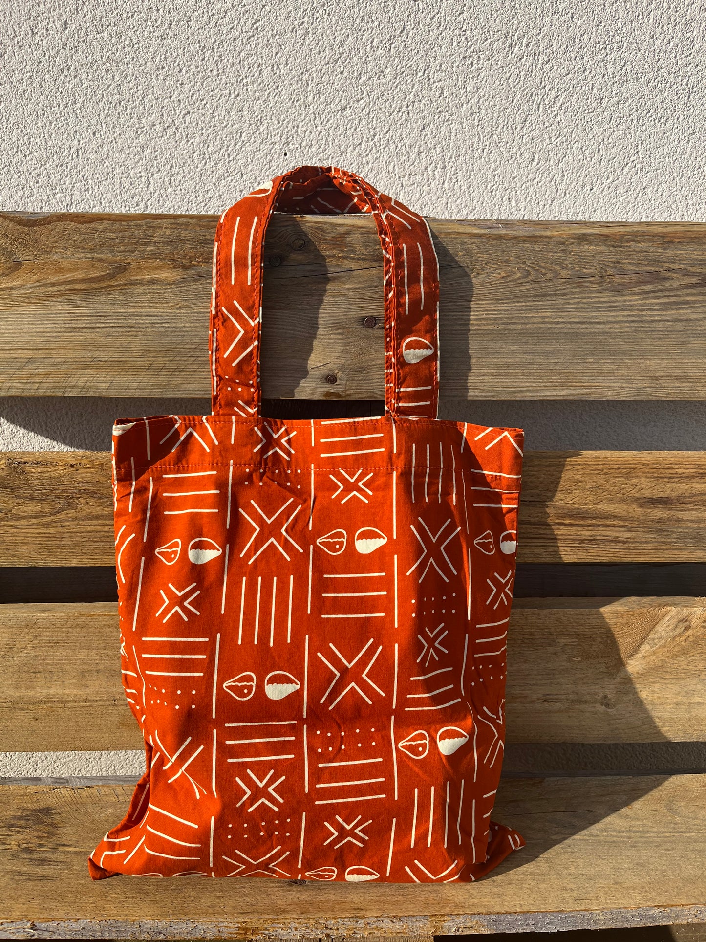 KPÊTÊ - Tote bag with orange and white bogolan patterns.